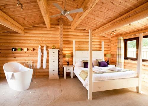 a log cabin bedroom with a bed and a bathtub at Weybread Lakes Lodges in Brockdish