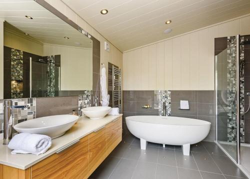 a large bathroom with two sinks and a tub at Weybread Lakes Lodges in Brockdish