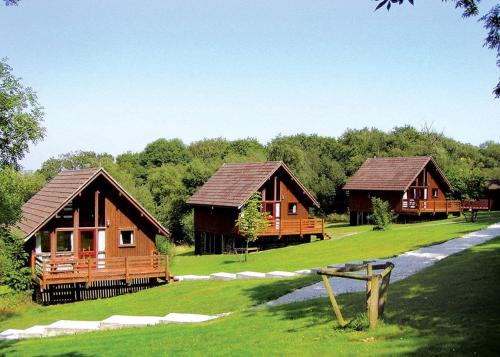 drie houten huisjes in een veld met bomen bij Eastcott Lodges in North Tamerton