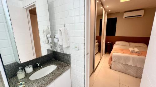 uma casa de banho com um lavatório e uma cama em EDF SEVILHA - Apartamento com 1 suíte climatizada e 2 Banheiros, Sala Climatizada a 300 metros da Beira-Mar de Ponta Verde - EXCELENTE LOCALIZAÇÃO em Maceió