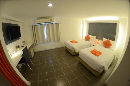 ein Hotelzimmer mit 2 Betten und einer Badewanne in der Unterkunft The Original Orange Hotel in Nakhon Si Thammarat