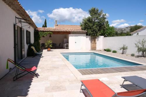 - une piscine dans une cour avec des chaises et une maison dans l'établissement charming vacation rental with heated pool at the foot of the alpilles, in aureille, close to the center of the village on foot, sleeps 6/8 people in provence., à Aureille