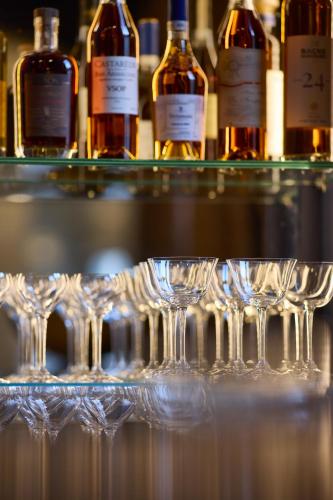 a group of wine glasses on a shelf with bottles at Maison 1896 in Beaune