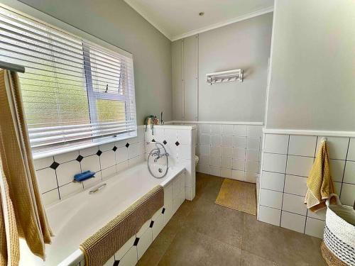 La salle de bains blanche est pourvue d'une baignoire et d'une fenêtre. dans l'établissement Lodge 62 Unparalleled view., à Mossel Bay