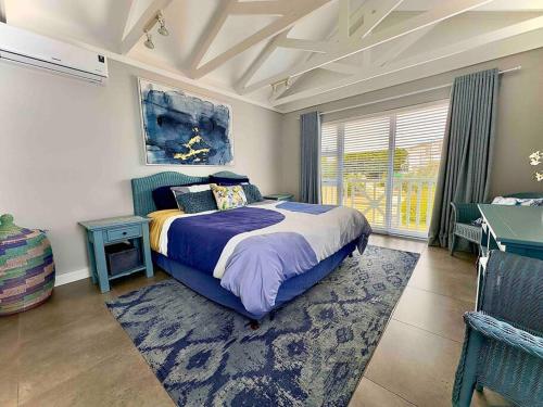 a bedroom with a bed and a table and a window at Lodge 62 Unparalleled view. in Mossel Bay