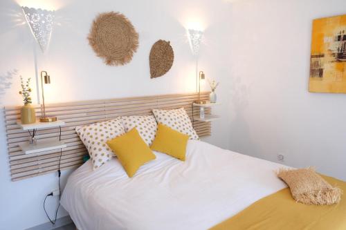 um quarto com uma cama branca e almofadas amarelas em Très jolie location vacances climatisée, 6 personnes proche des Baux de Provence, située au coeur des Alpilles à Mouriès, LS1-312 Clarta em Mouriès