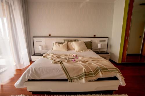 ein Schlafzimmer mit einem großen weißen Bett mit Kissen in der Unterkunft Bairos House - Coastal Escape in Ribeira Brava