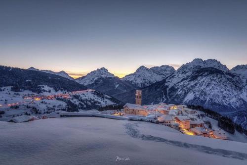 a small town in the mountains with snow covered mountains at Hotel Tre Pini in Danta