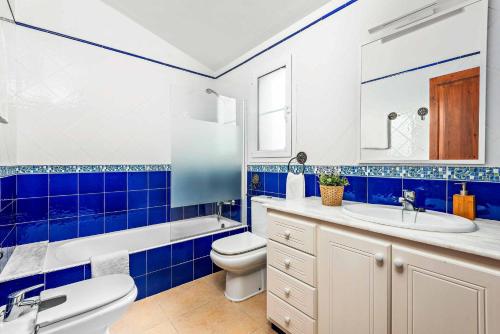 een blauwe en witte badkamer met een toilet en een wastafel bij Villa Galdana Rosa in Cala Galdana