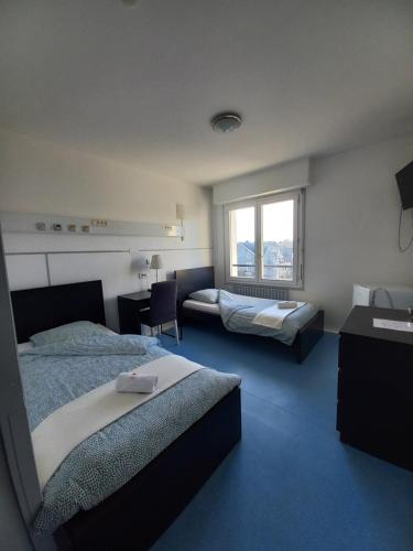 a hotel room with two beds and a window at Hôtel Labat in Orthez