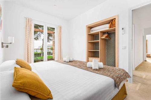 een witte slaapkamer met een groot bed met gele kussens bij Villa Gabriela in Santo Tomás