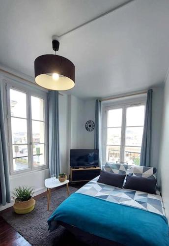une chambre avec un lit bleu et deux fenêtres dans l'établissement L'Ancre du port, à Dieppe