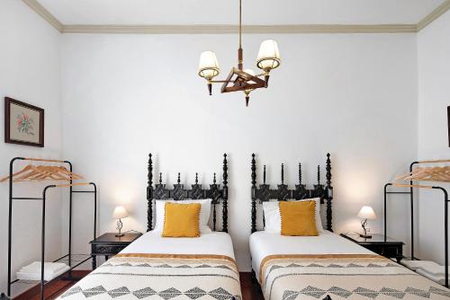 two twin beds in a room with a chandelier at Sé Heritage in Angra do Heroísmo