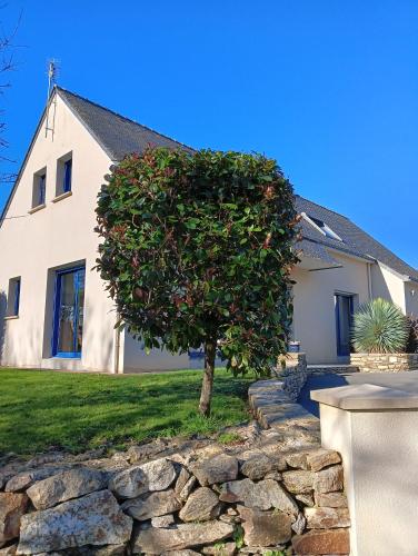 a tree in front of a house with a stone wall at Maison au calme et proche de la mer in Arzal