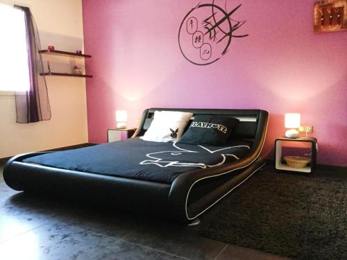 a large bed in a room with a pink wall at very pretty contemporary villa with heated pool located in aureille in the alpilles, close to the center on foot. sleeps 4. in Aureille