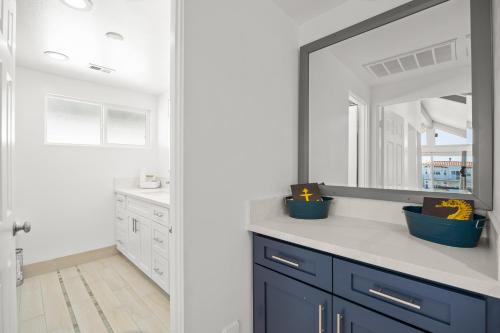 een badkamer met blauwe kasten en een grote spiegel bij Harbor Living in Oxnard