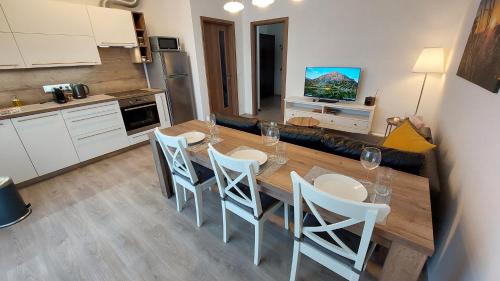 cocina con mesa de madera y sillas blancas en Apartmán Trilobit, en Beroun