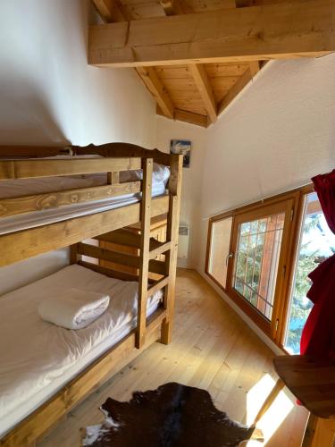 une chambre avec deux lits superposés et une fenêtre dans l'établissement PLEIN SUD AMBIANCE CHALET, à Valloire