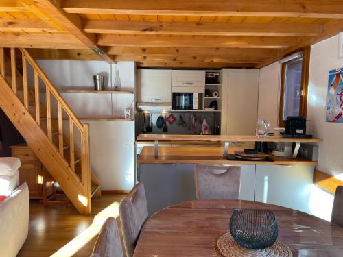 une cuisine et une salle à manger avec une table et un escalier dans l'établissement PLEIN SUD AMBIANCE CHALET, à Valloire
