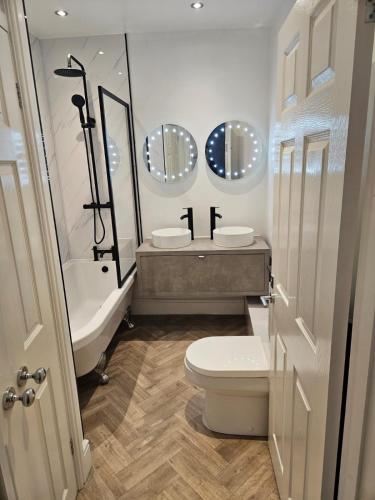 a bathroom with a toilet and a sink and two mirrors at St James By the Quay in Ilfracombe