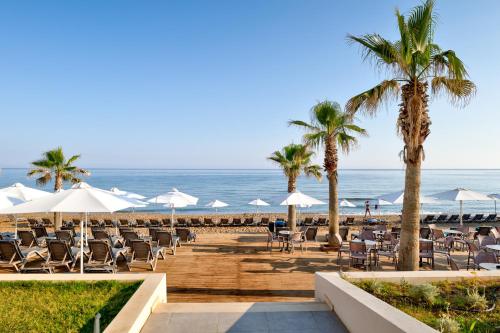 einen Strand mit Liegestühlen und Sonnenschirmen und dem Meer in der Unterkunft White Olive Elite Rethymno in Sfakaki