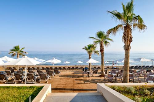 a beach with chairs and umbrellas and the ocean at White Olive Elite Rethymno in Sfakaki