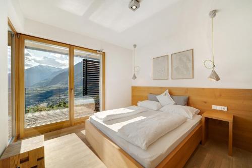 een slaapkamer met een bed en een groot raam bij Panoramasuite - Dahoam in Schenna