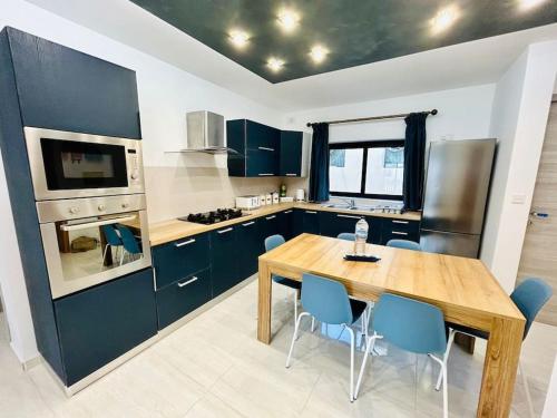 a kitchen with a wooden table and blue chairs at Cosy Home Close to the Sea, King-Size Bed in St Paul's Bay