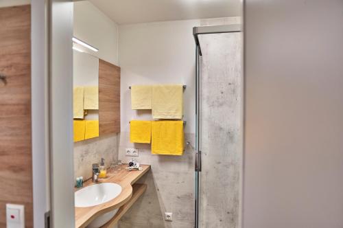 bagno con lavandino, doccia e asciugamani gialli di Landhotel Gruber a Waldmünchen