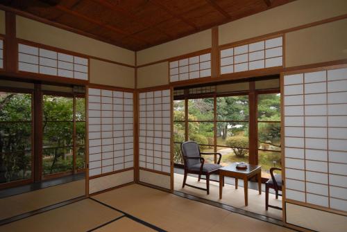 an empty room with a table and chairs and windows at Sansuien in Yamaguchi