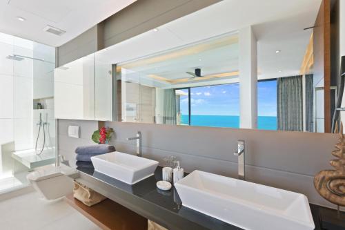 a bathroom with two sinks and a large mirror at Sukkho Samui Estates in Chaweng Noi Beach