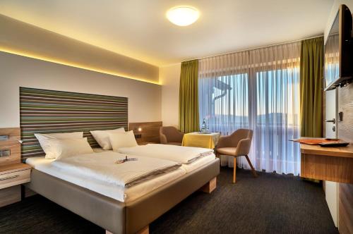 ein Hotelzimmer mit einem Bett und einem großen Fenster in der Unterkunft Landhotel Gruber in Waldmünchen