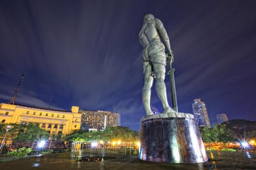a statue of a man standing in a city at night at Riviera Mansion Hotel in Manila