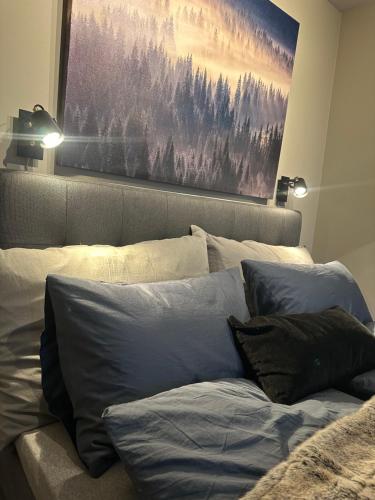 a bed with pillows and a painting on the wall at TheNorthernExplorer Penthouse in Tromsø