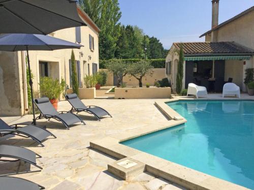 - une piscine avec des chaises et un parasol à côté d'une maison dans l'établissement authentic provencal mas with pool, in the countryside of the village of sénas, close to the luberon and the alpilles, sleeps 8., à Sénas