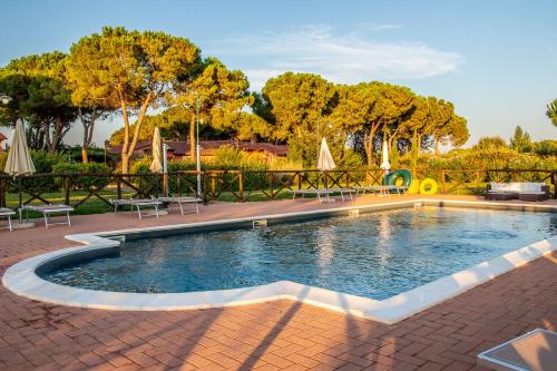 a pool with chairs and umbrellas in a park at Agriturismo Il Sogno in Castiglione del Lago