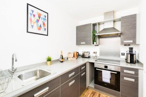 a kitchen with gray cabinets and a sink at Spacious City Centre Apartment - Balcony - Smart TV - WIFI- 448A in Birmingham