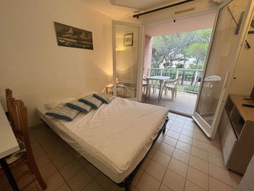 een slaapkamer met een bed en een balkon met een tafel bij Appartement Saint-Aygulf, 1 pièce, 4 personnes - FR-1-226A-89 in Saint-Aygulf