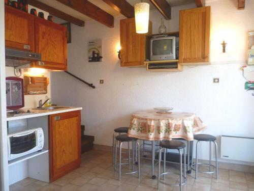 une cuisine avec une table avec des chaises et un micro-ondes dans l'établissement Charmante maison proche plage avec parking privé et terrasse - FR-1-387-84, à Marseillan