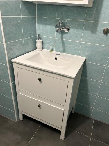 lavabo blanco en un baño con azulejos azules en Apartmány u vleku, en Karlova Studánka