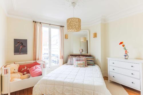 Schlafzimmer mit einem weißen Bett und einem Spiegel in der Unterkunft Beautiful 95m2 flat in the heart of Neuilly Sur Seine in Neuilly-sur-Seine