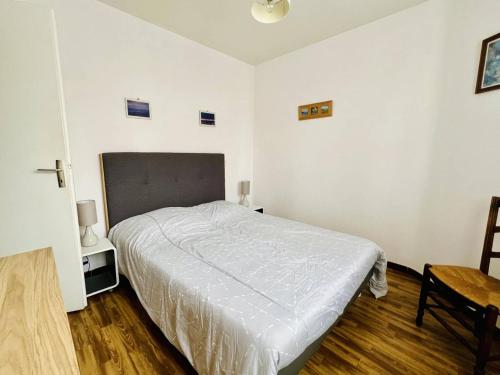 1 dormitorio blanco con 1 cama y 1 silla en Appartement Cambo-les-Bains, 2 pièces, 2 personnes - FR-1-495-112, en Cambo-les-Bains