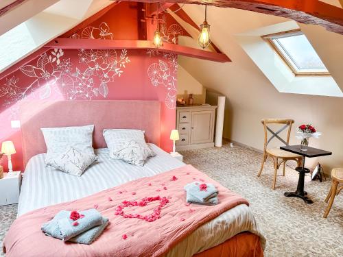 una camera da letto con un grande letto e pareti rosa di Domaine du Grenier a Yffiniac