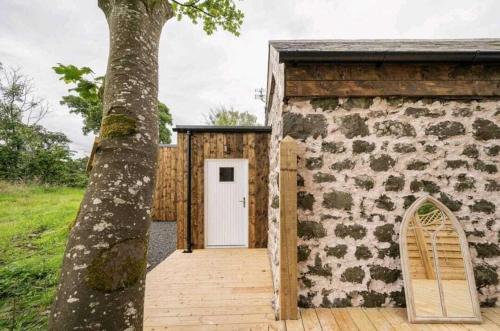a building with a white door next to a tree at Squirrel Cottage in Ballymena