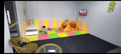 un niño sentado en un sofá en una sala de juegos en Green Forest Resort, en Setiu