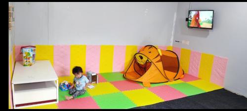 un niño pequeño jugando en una habitación con un juguete en Green Forest Resort, en Setiu