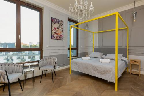 a bedroom with a yellow canopy bed and two chairs at Royal Garden Apartment in Wilanow by Renters Prestige in Warsaw