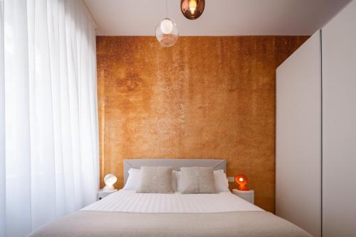 a bedroom with a white bed and a orange wall at San Babila Design Apartment R&R in Milan