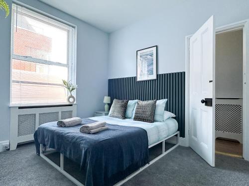 a bedroom with a bed with blue walls and a window at Stylish 3-bedroom home in Canterbury City-Centre - Superb Location! in Canterbury