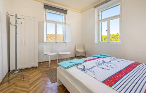 a bedroom with a bed and two windows at Awesome Home In Kolocep With Heated Swimming Pool in Koločep